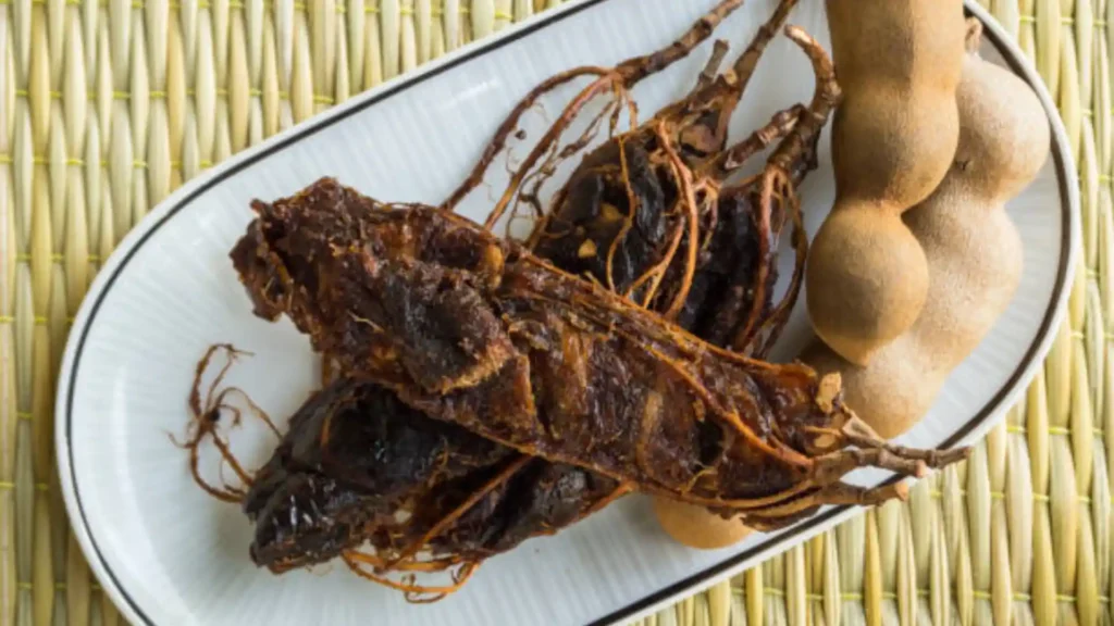 Finished Mexican tamarind candy in push-up tubes with tamarind strands, styled with Tajín, lemon wedges, and tamarind pods